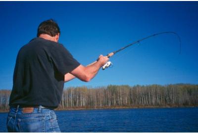 man wearing black shirt and jeans casting his fishing rod in lake