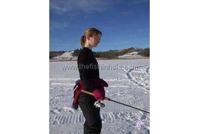 woman standing in snow holding ice fishing rod