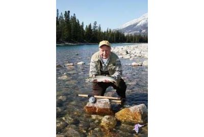 Neil Waugh kneeling down holding a Athabasca River winter bull trout