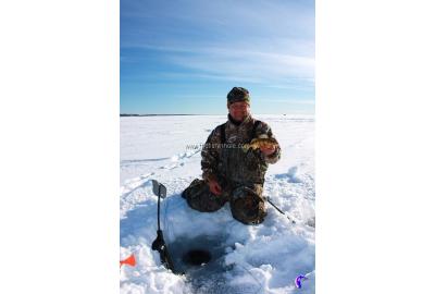 fishing author fred noddin sits by ice fishing hole and holds out catch