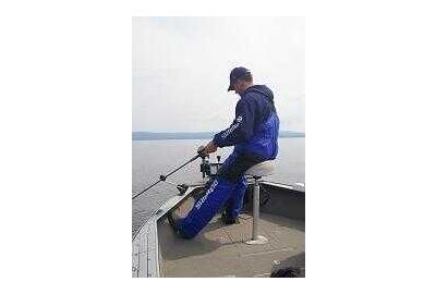 fishing man sits on a boat stool 