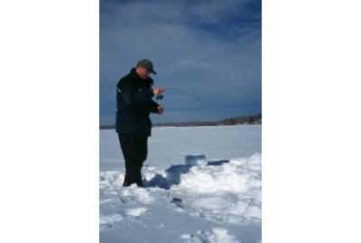 man standing in snow ice fishing