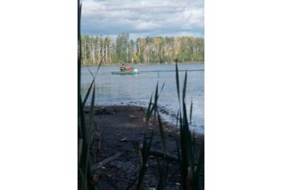 lake shore boat seen in the distance with person sitting in it during day time