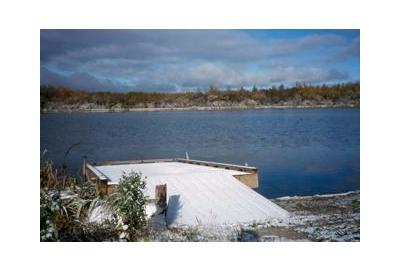 blue lake with snow covered dock winter treeline