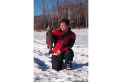 man holding trout kneeling on snow