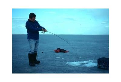 man ice fishing cloudy blue tint sky