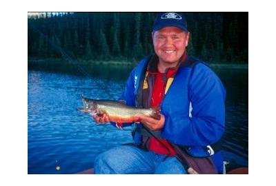 man wearing blue jacket holding brookie fish