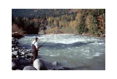 man fishing on large rocky shore of turbulent river