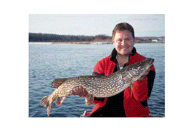 man holding pike horizontally in front of body of water