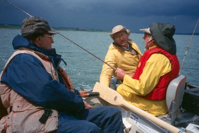 3 fishermen sitting in a boat summer