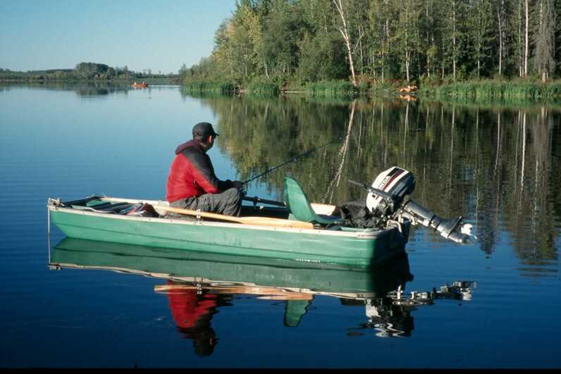 fisherman in a small green boat with motor on a lake