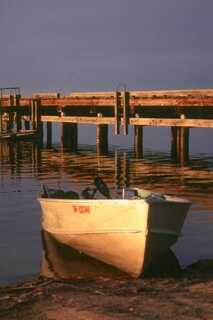 small boat docked on shore during sunset golden hour