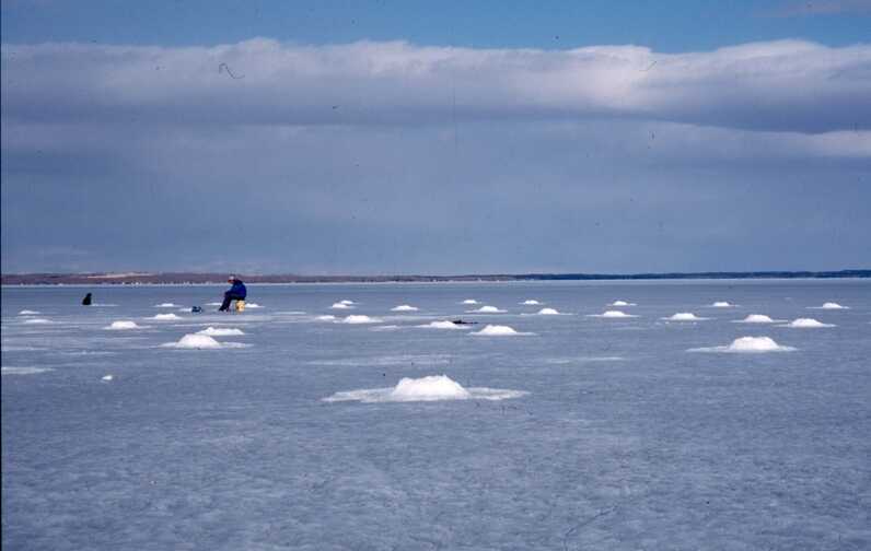 ice fishing cloudy sky fisherman in the distance 