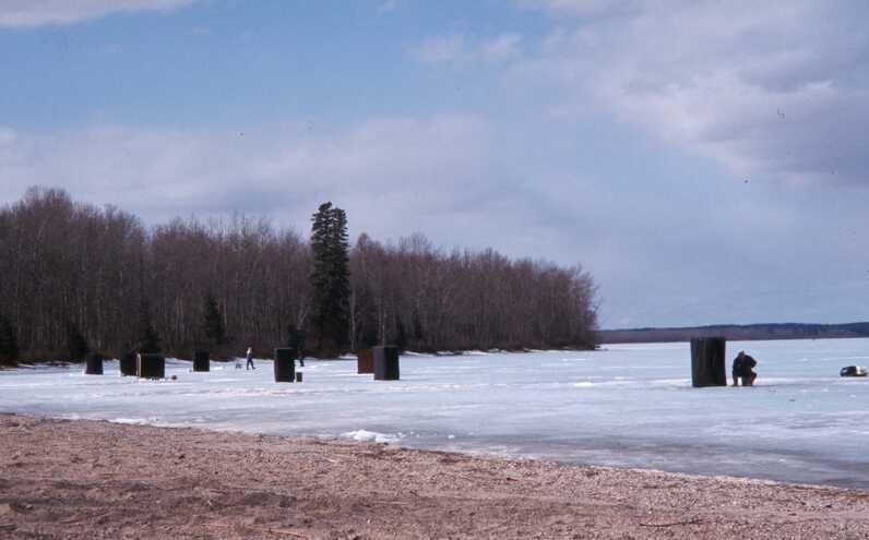 black ice fishing tents scattered across frozen lake