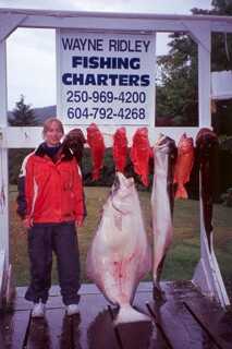 girl standing next to sign that says wayne ridley fishing charters and several large fish displayed