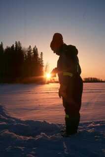 silhouette of person standing in snow during sunset