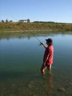 person standing in the river holding up fishing rod 