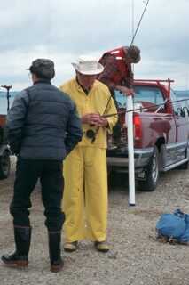 three fishermen prepare to go fishing grabbing items from their truck and setting up their fishing rods