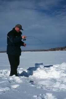 man standing in snow ice fishing