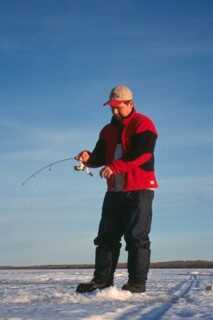 man wearing red jacket and cap standing on snow ice fishing