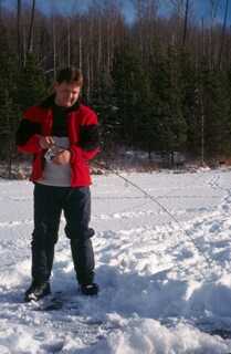 man standing in snow holding long fishing rod