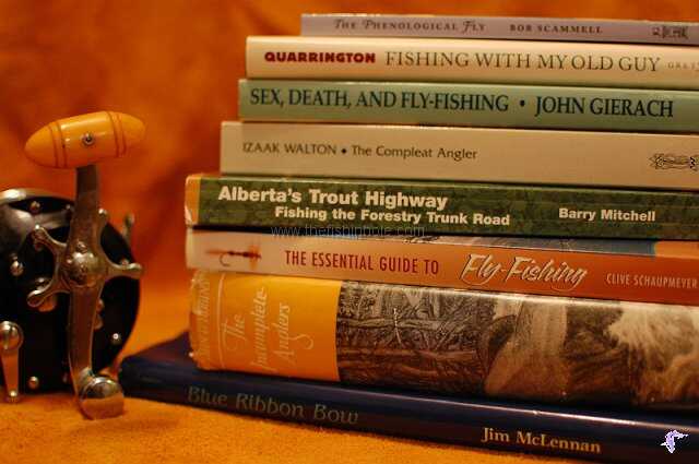 stack of 8 books of varying sizes set next to fishing reel 