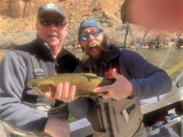 two guys holding fish one guy has a big open mouth smile