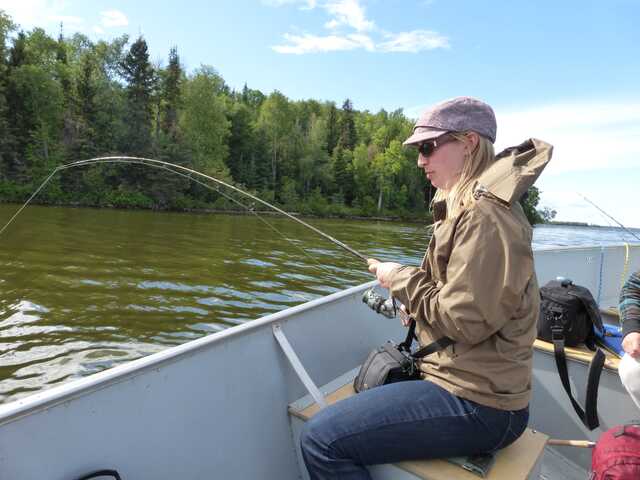 left side view of woman sitting in boat and fishing